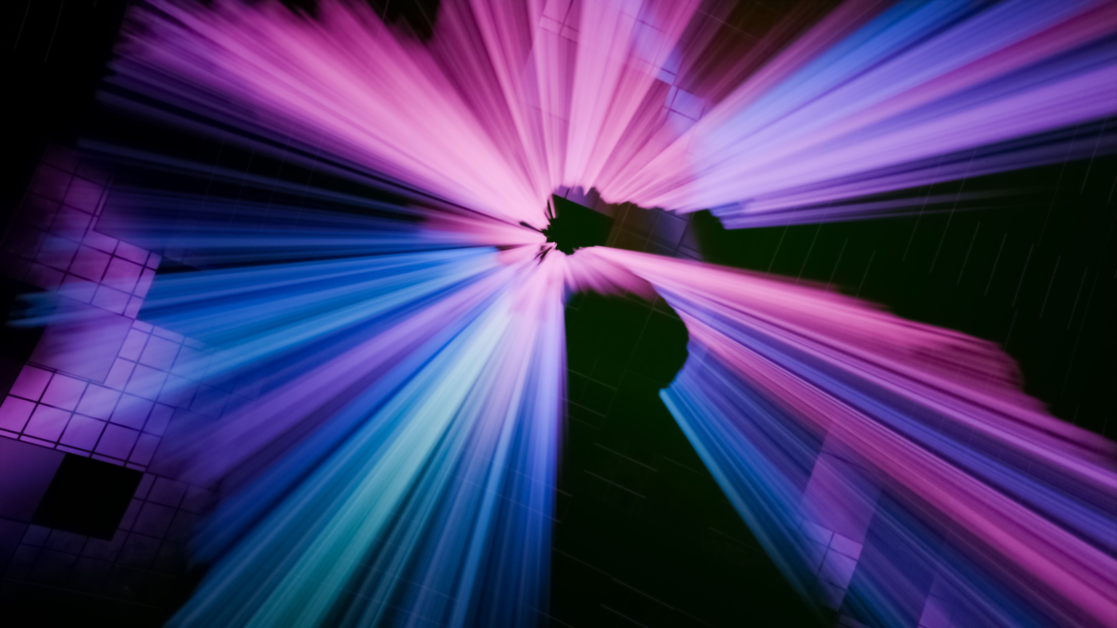 Abstract photo of pink, purple and blue light streaking outward from a single point, like motion at high speed.